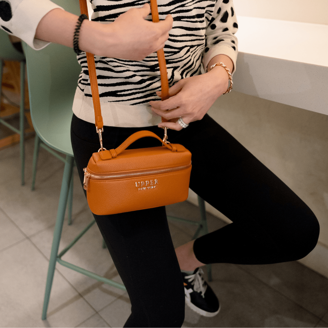 Mini bag in tan held at the waist by a mom at a cafe on a night out