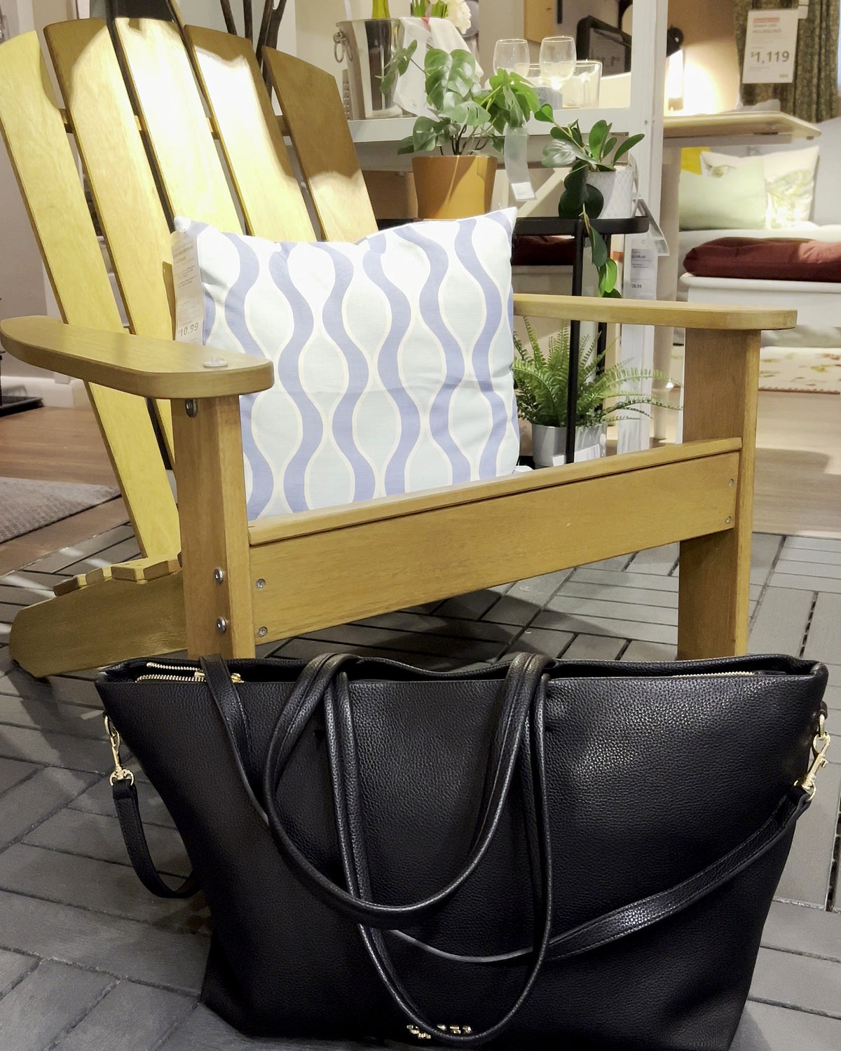 Carry-on tote in black resting by a patio chair, dressed-up everyday style